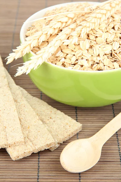 Cuenco verde lleno de copos de avena con cuchara de madera — Foto de Stock