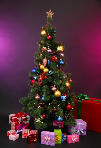 Geschmückter Weihnachtsbaum mit Geschenken auf dunklem Hintergrund — Stockfoto