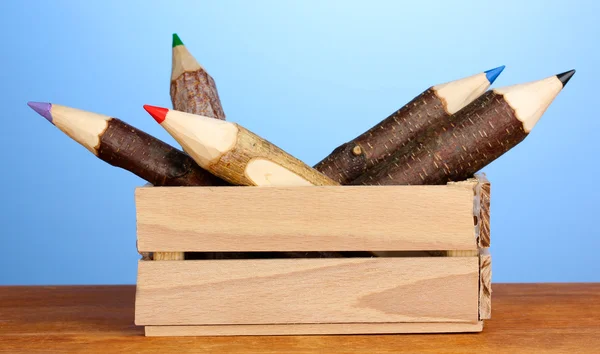 Barevné dřevěné tužky v poli na modrém pozadí — Stock fotografie
