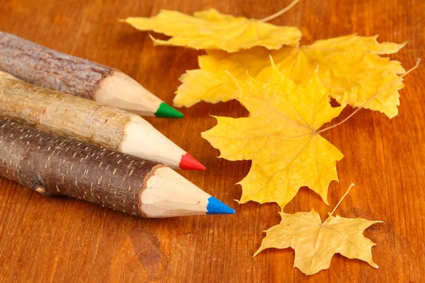 Kleurrijke houten potloden met herfst bladeren op houten tafel — Stockfoto