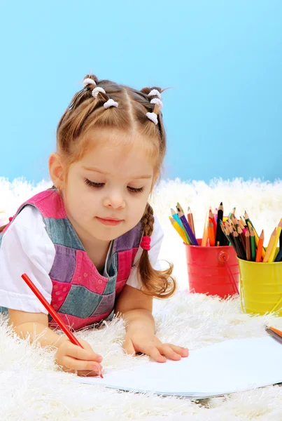 Söt liten flicka som leker med multicolor pennor, på blå bakgrund — Stockfoto