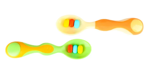 Cucchiai di plastica con pillole di colore, isolati su bianco — Foto Stock