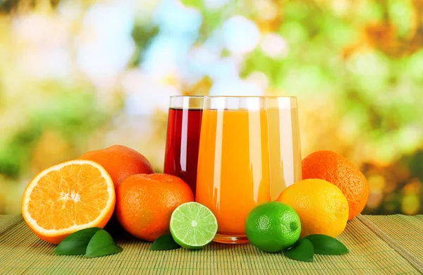 Verres de juise avec des feuilles et des fruits sur la table sur fond lumineux — Photo