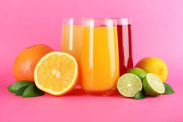 Glasses of juise with leafs and fruits on pink background — Stock Photo, Image