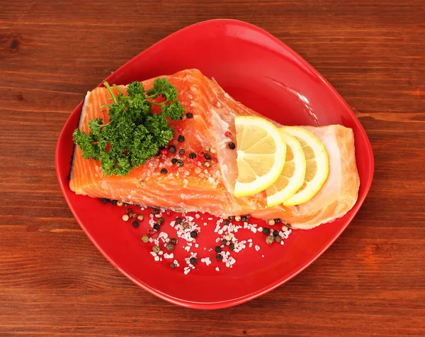 Fresh salmon fillet with herbals and lemon slices on plate,on wooden background — Stock Photo, Image