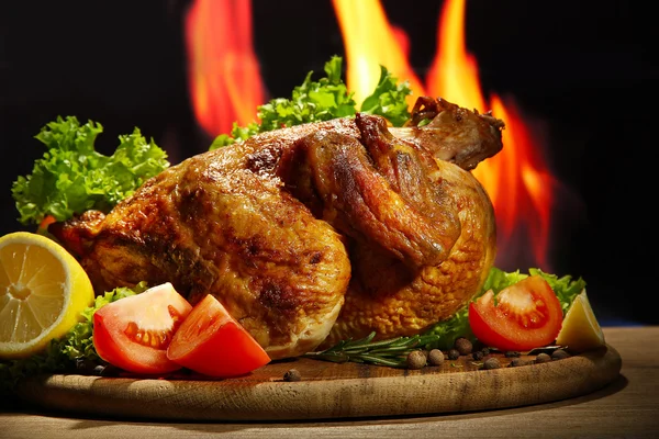 Alev arka plan üzerinde tabakta sebze ile bütün kavrulmuş tavuk — Stok fotoğraf