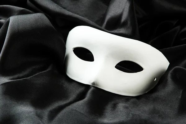 White mask, on black silk fabric — Stock Photo, Image