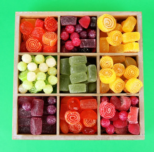 Caramelle multicolore in scatola di legno, su sfondo colore — Foto Stock