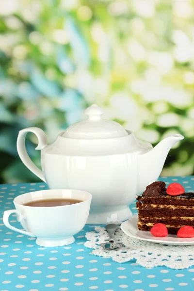 Teiera, tazza di tè e deliziosa torta su sfondo naturale — Foto Stock