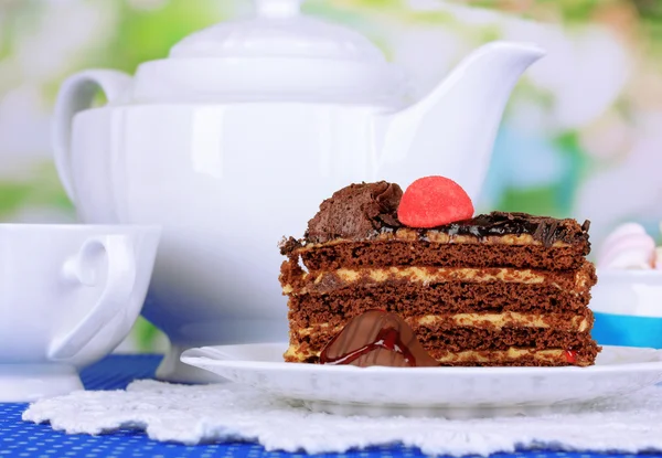 Théière, tasse de thé et délicieux gâteau sur fond naturel — Photo