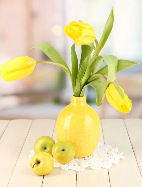 Gele tulpen in de vaas op houten tafel op kamer achtergrond — Stockfoto