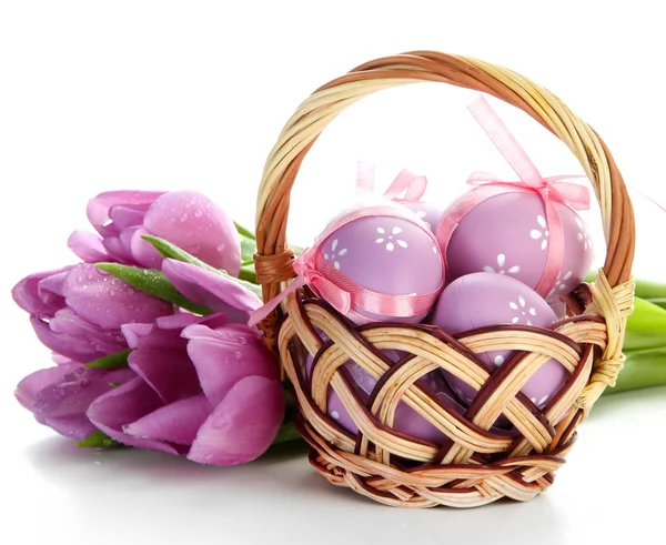 Huevos de Pascua brillantes en cesta y tulipanes, aislados en blanco —  Fotos de Stock