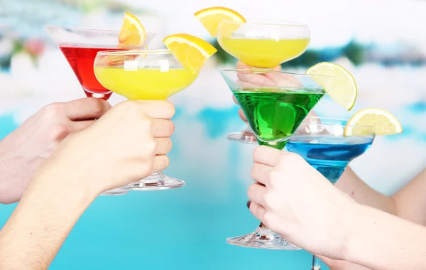 Cocktails i händerna på pool bakgrund — Stockfoto