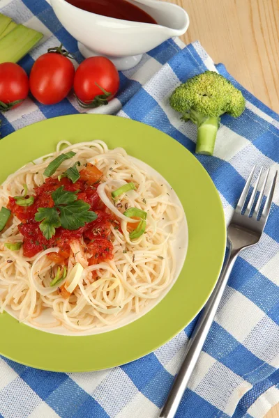 Tasty spaghetti with sauce and vegetables on plate on wooden table close-up — Stock Photo, Image