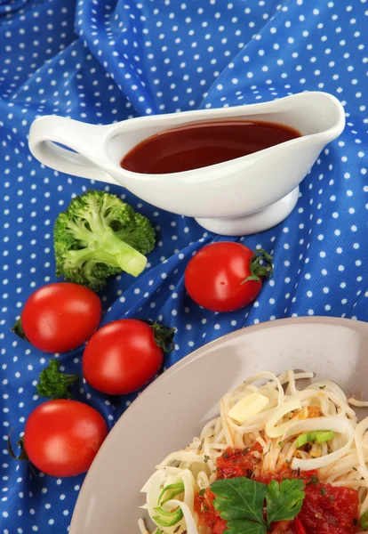 Вкусные спагетти с соусом и овощами на тарелке на деревянном столе крупным планом — стоковое фото