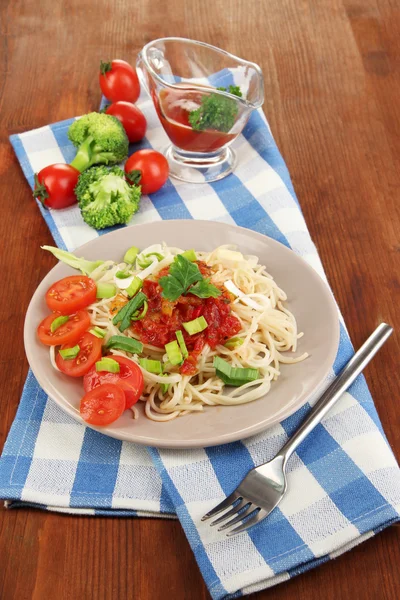 Espaguete saboroso com molho e legumes na placa na mesa de madeira close-up — Fotografia de Stock