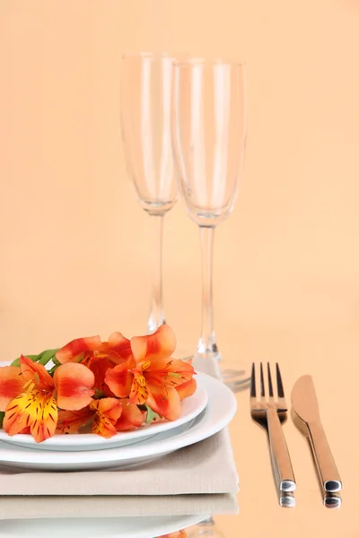 Festive table setting with flowers on peachy background — Stock Photo, Image