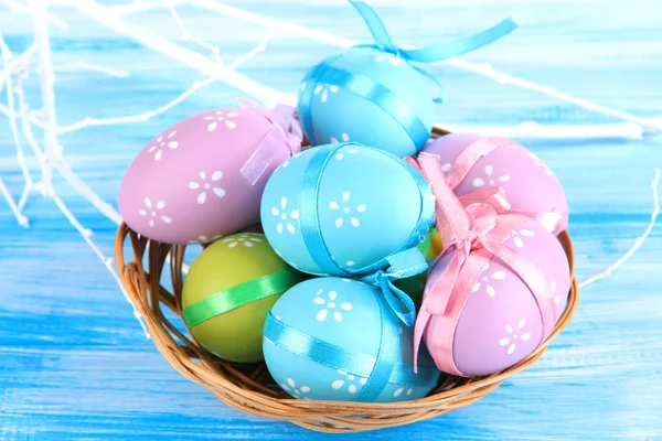 复活节彩蛋在篮子里，在蓝色木制背景 — 图库照片
