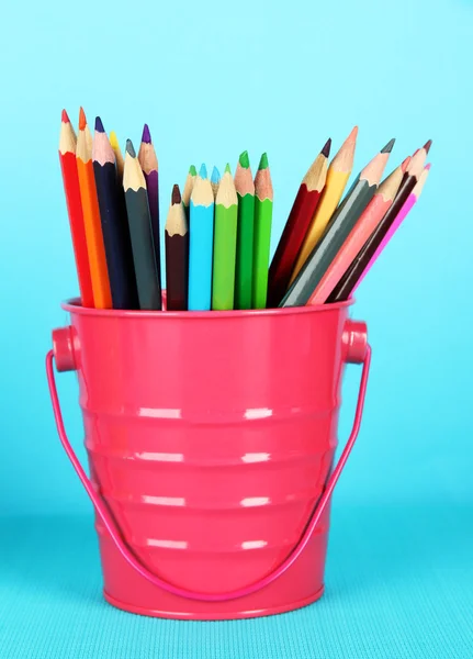 Kleurrijke potloden in emmer op blauwe achtergrond — Stockfoto