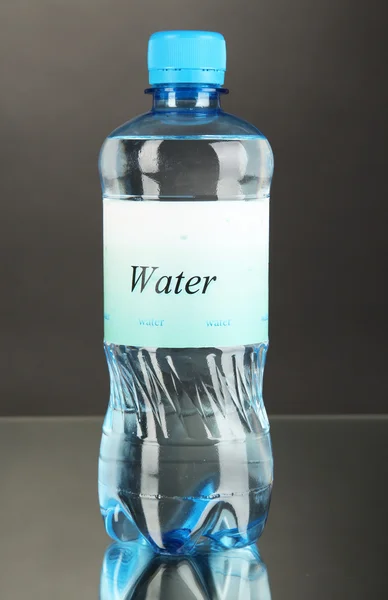 Water bottle with label on grey background — Stock Photo, Image