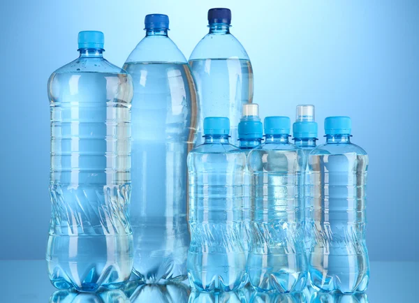 Olika vattenflaskor på blå bakgrund — Stockfoto