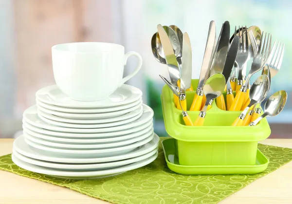 Piatti, forchette, coltelli, cucchiai e altri utensili da cucina su tovagliolo di colore, su sfondo brillante — Foto Stock