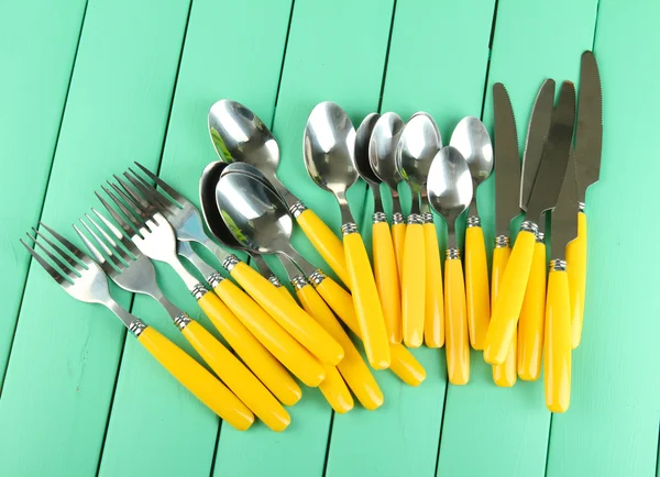 Tenedores, cuchillos, cucharas sobre fondo de madera de color —  Fotos de Stock