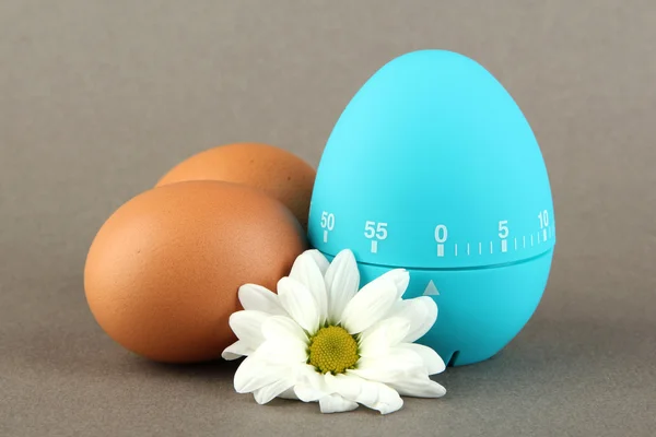 Temporizador de ovo azul e ovos, no fundo de cor — Fotografia de Stock