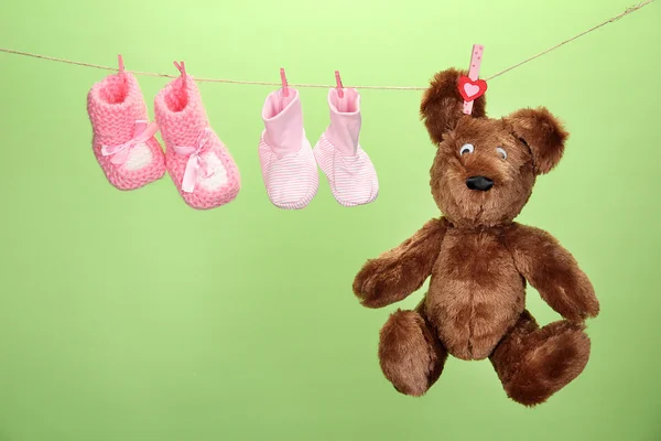 Baby booties hanging on clothesline, on color background — Stock Photo, Image