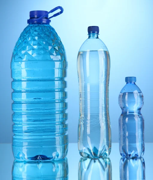 Different water bottles on blue background — Stock Photo, Image