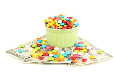 renkli bir kase üzerinde beyaz izole dolarlık banknotlar üzerinde duran şekerler