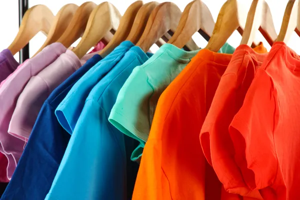 Scelta di vestiti di diversi colori su appendini in legno, isolati su bianco — Foto Stock
