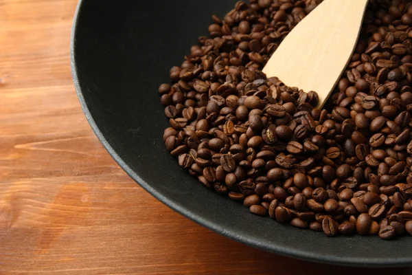 Poêle wok noir avec grains de café sur table en bois, fermer — Photo