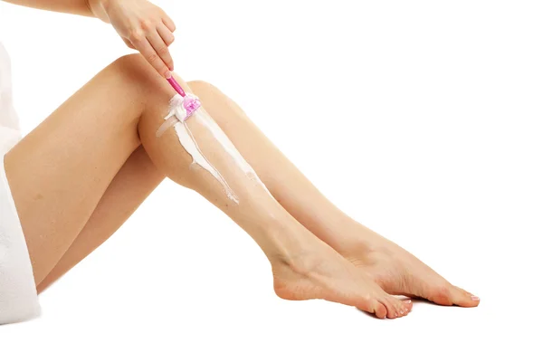 Mooie vrouw is scheren haar been, geïsoleerd op wit — Stockfoto