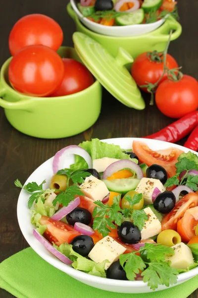 Греческий салат в тарелке на деревянном столе — стоковое фото