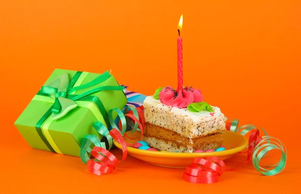 Colorful birthday cake with candle and gifts on orange background — Stock Photo, Image