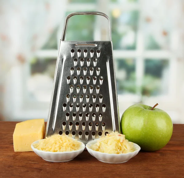 Metal grater and cheese, apple on bright background — Stock Photo, Image