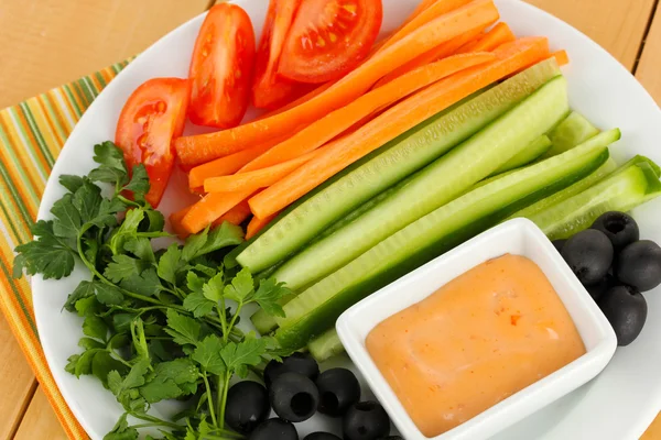 Diverse råa grönsaker pinnar i plattan på träbord närbild — Stockfoto