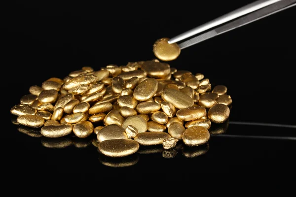 Pincet houden gouden steen geïsoleerd op zwart — Stockfoto