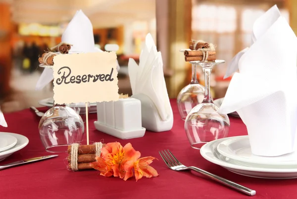 Reserved sign on restaurant table with empty dishes and glasses — Stock Photo, Image