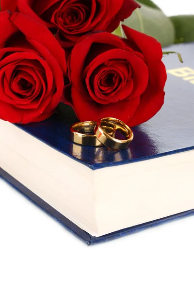 Anneaux de mariage avec roses sur bible isolé sur blanc — Photo