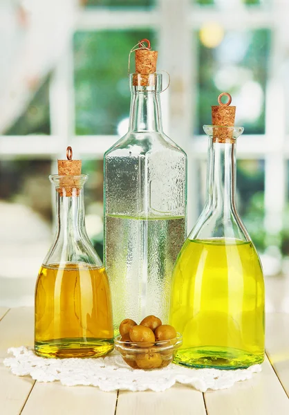 Original glass bottles with salad dressing on wooden table on window background — Stock Photo, Image