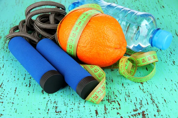 Naranja con cinta métrica, saltar la cuerda y la botella de agua, sobre fondo de madera color —  Fotos de Stock