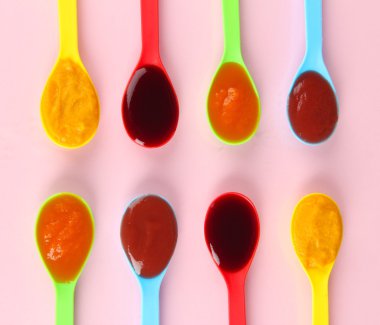 Bebek püresi pembe bir arka plan üzerine kaşık içinde