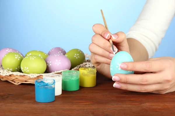 Young woman painting Easter eggs, on color background — Stock Photo, Image