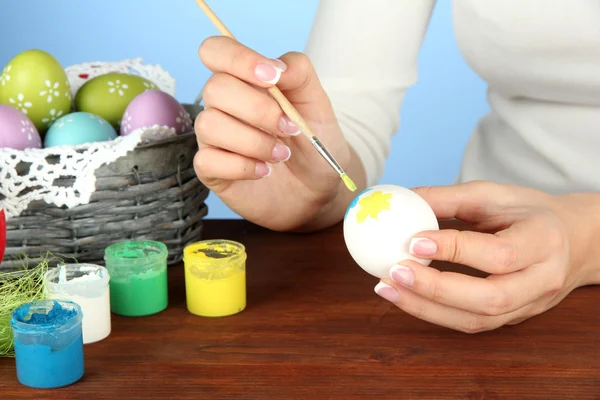 Young woman painting Easter eggs, on color background — Stock Photo, Image