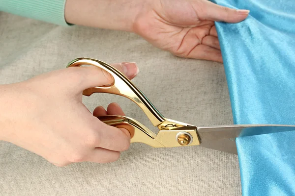 Seamstress corte tecido azul no fundo tecido bege — Fotografia de Stock