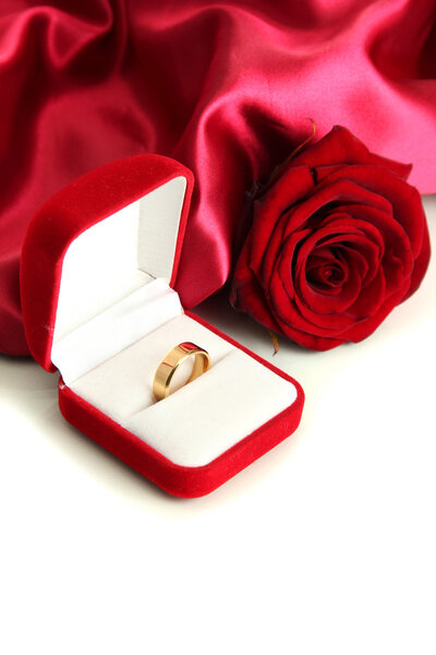 Beautiful box with wedding ring and rose on red silk background