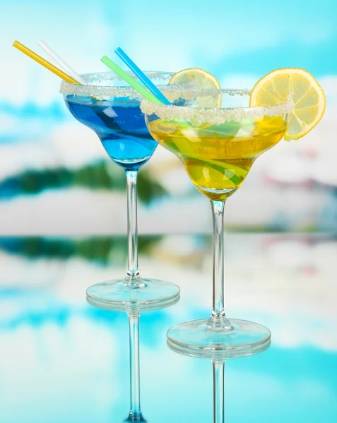 Gele en blauwe cocktails in glazen op blauwe natuurlijke achtergrond — Stockfoto