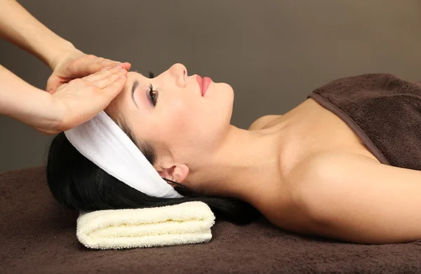 Piękna młoda kobieta w salonie spa, biorąc masaż głowy, na ciemnym tle — Zdjęcie stockowe